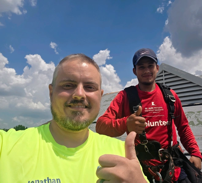 Jonathan Stephenson and a crew member in a St. Jude Memphis Marathon volunteer shirt on a roof in Memphis, Tennessee
